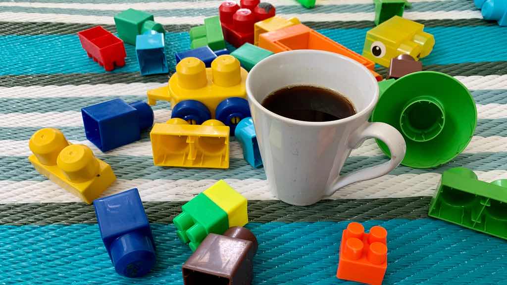 Half empty coffee cup amidst scattered plastic toy bricks.